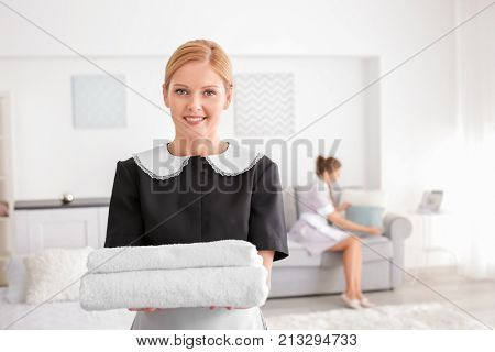 Beautiful chambermaid with towels in room