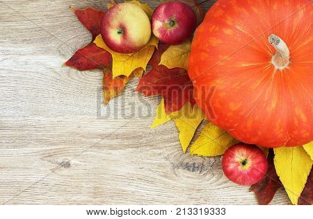 Autumn composition. Pumpkin apples and leaves on a wooden background.