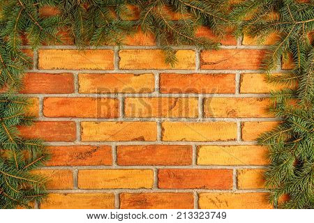 Christmas twigs spruce, located on the background of the old brick wall. Festive background in vintage style with free space for text. Christmas green pine spruce spruce branch on brick background.
