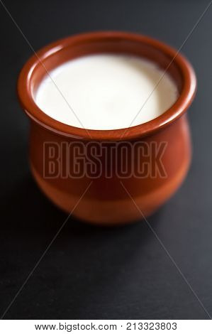 Sour cream or natural Cottage cheese curd in clay pot on dark background. Traditional Cuajada yogurt cream