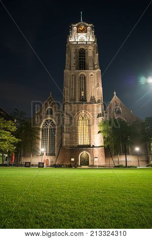 Gothic Saint Lawrence Church contrasts with bright green lawn at night long exposure and lens flare from right street light