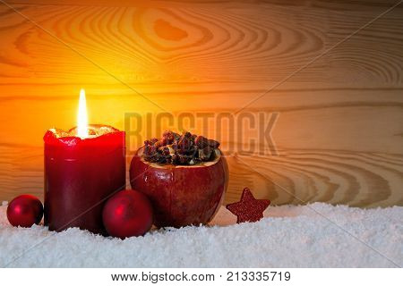 Avent candle and roasted apple with raisins isolated on wood background.