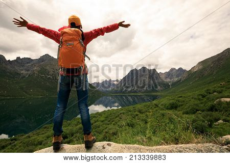 cheering young backpacking woman hiking in mountains