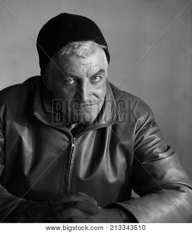 masculine middle-aged man in a knitted black hat and leather jacket in style of analog photography
