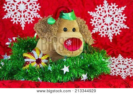 New Year Toy Dog Surrounded By Decorative Christmas Elements And Fir Branches On Red Background