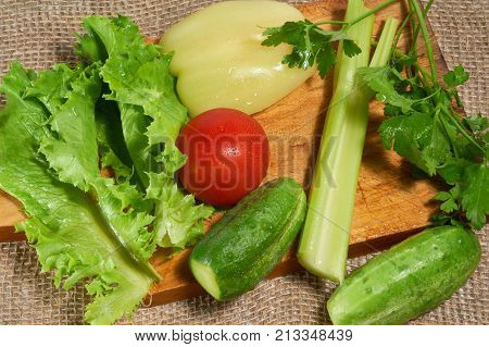 Salad tomatoes peper cucumbers smallage and parsley on cutting board