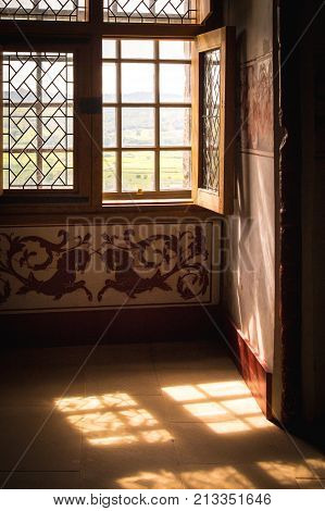 Sunlight streams through an old wooden window in an old english house with ornate decor