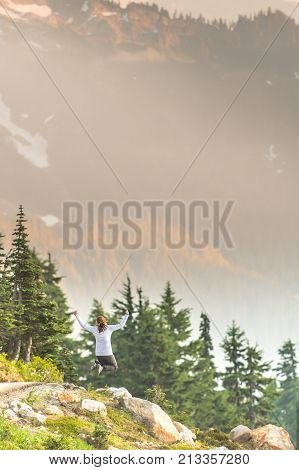 Bright Afternoon Sun Shines on Woman Leaping in cascade mountains