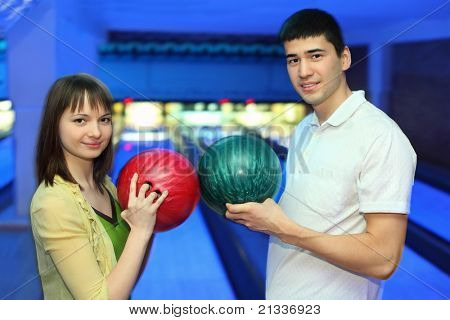 Flicka och ungdom vände sig till varandra och gränsar bollar för bowling