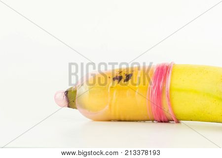 color pink used condom with sperm cover on yellow fresh banana isolated on white background.