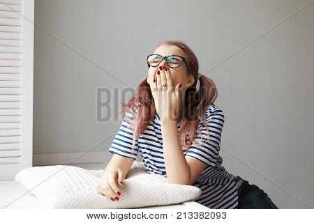 Boredom and fatigue concept. Picture of trendy looking student girl in glasses throwing head back and yawning covering mouth with hand feeling sleepy and tired after sleepless night out with friends
