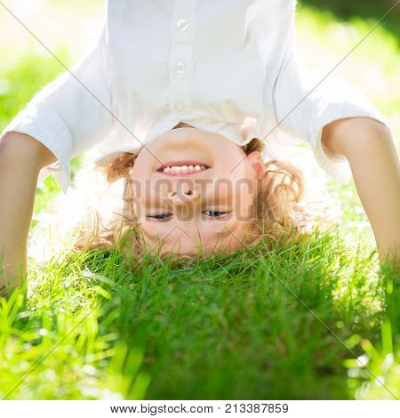 Happy smiling kid playing on green grass in spring park. Healthy lifestyle concept. Children`s fitness