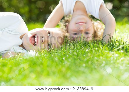 Happy children standing upside down on green grass in spring park. Healthy lifestyles concept.