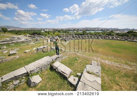 A man in a striped T-shirt looking at ruins of the ancient Roman amphitheater 