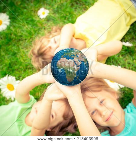 Children holding 3D planet in hands against green spring background. Earth day holiday concept. Elements of this image furnished by NASA
