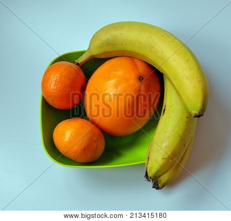 persimmon, banana, mandarin in a green toiler