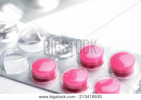Hands tearing blister pack of green and yellow capsule medical pill.