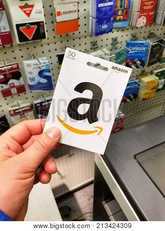 MONTREAL CANADA - NOVEMBER 7 2017: 50 dollar Amazon gift card in a hand on gift cards background. Amazon is an American electronic commerce and cloud computing company based in Seattle Washington