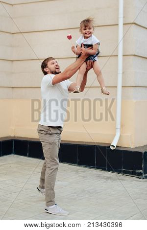father holds little daughter in her arms on the background of the building 1