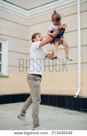 father holds little daughter in her arms on the background of the building 1
