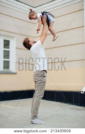 father holds little daughter in her arms on the background of the building 1