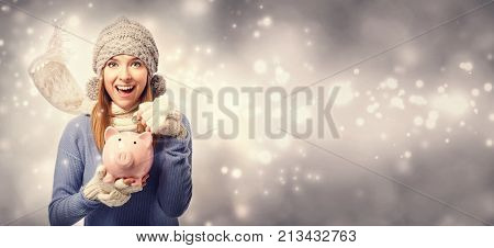 Happy young woman depositing money into her pink piggy bank