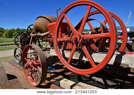 Red painted huge fly wheel of a gas engine which operated a cement mixer on wheels