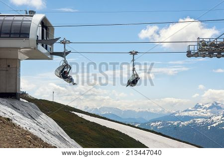 Rosa Khutor, Sochi, Russia - June 09, 2017: Funicular at the Rosa Khutor - Russian ski resort in Sochi. Tourists on a ski lift. Snowy caucasus mountains on background.