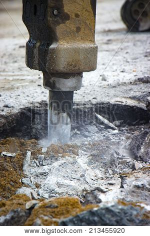 Excavator breaking and drilling the concrete road for repairing close up