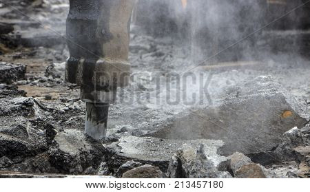 Excavator breaking and drilling the concrete road for repairing close up
