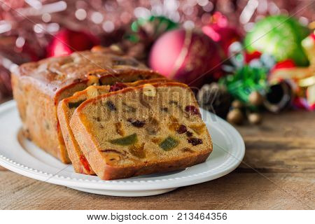 Homemade delicious soft and moist rum fruits cake or Christmas fruits cake with rich dried fruit and nuts slices on wood plate put on wood table with copy for party and celebration. Bakery concept. Christmas fruits cake ready to served.