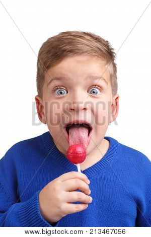 Boy in blue sweater in ecstasy licks lollipop close-up on white isolated background
