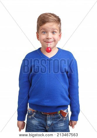 A boy in a blue sweater and jeans emotionally happily holds a lollipop in his mouth for a wand on a white isolated background
