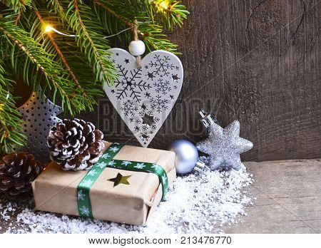 Christmas decoration with fir tree,fift, garland lights,white christmas heart and pine cone on old wooden background.Winter holidays,Merry Christmas,Happy New Year concept.Copy space.Selective focus.