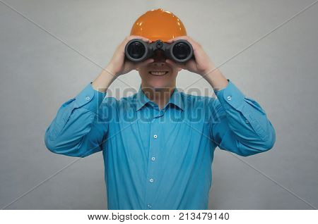 Engineer holding binoculars in hands and looking ahead isolated. Geodesist explore construction site.