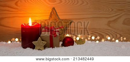 Avent candle and christmas decoration isolated on wood background. Christmas background with snow, candle and gift box.