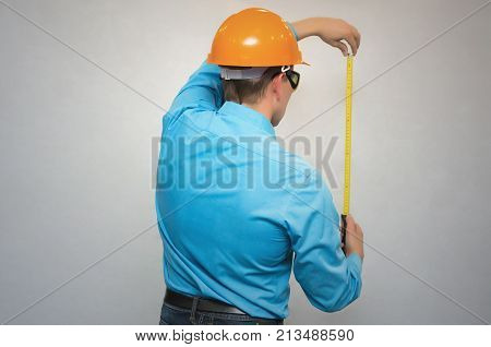 Builder worker holding in hands construction roulette and measures copy space in front of him back view isolated. Engineer takes measurements.
