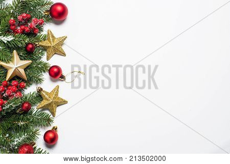 Christmas background. Snow Fir tree branch red balls golden star and berries on white background isolated. Top view with copy space.