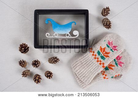Winter holidays celebrating. Frame with snow-covered sledges bumps and knitted mittens with ornament.