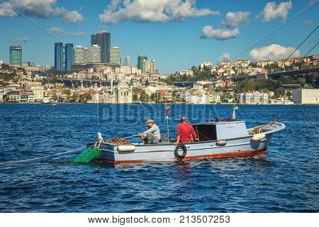ISTANBUL TURKEY: Trappers of rapans in their boat on the Bosporus and Ortakoy mosque on background on October 10 2017