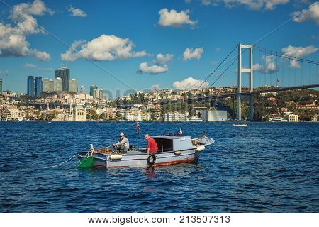 ISTANBUL TURKEY: Trappers of rapans in their boat on the Bosporus Ortakoy mosque and Bosphorus Bridge on background on October 10 2017