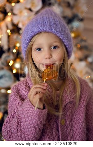 girl in the sweater and the hat is from candy in the new year with a Christmas tree
