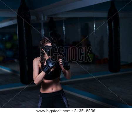 Young fighter boxer fit girl in VR glasses wearing boxing gloves in training. Boxing game in virtual reality 360 degrees. Futuristic gaming