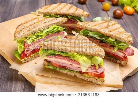 Delicious Ham, Salami, Cheese and Vegetables Sandwiches on Toasted Whole Grain Bread Isolated on white