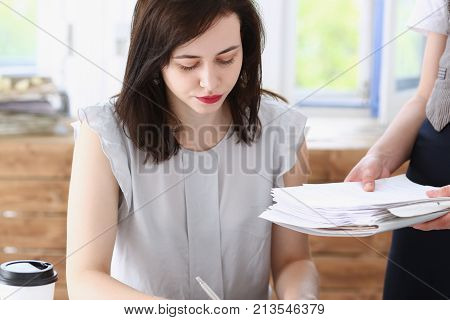 Female employee show pack of documents to busy male manager or boss give extra work to executor. White collar portrait contract approval headache and depression irs lot of new problems concept