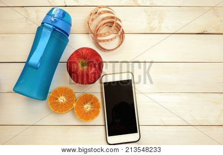 Fitness concept,exercise for losing weight with sport set,drinking bottle ,fresh fruit ,smartphone on white wood floor. Top view for copy space