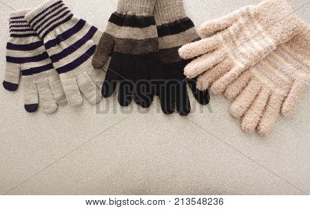 Warm woolen knitted gloves,three of colorful style on sparkling background,concept for winter's clothes on top view for copy space