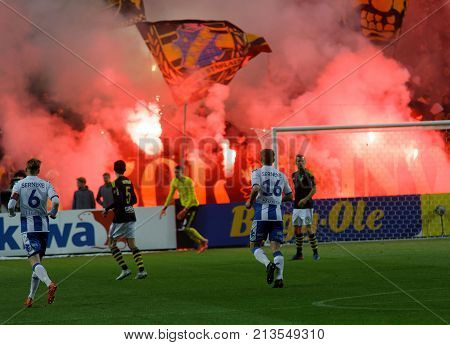 SOLNA SWEDEN - OCT 30 2017: The supporters to the soccer team AIK waving flags starting red fire giving lots of smoke. October 30 2017SolnaSweden