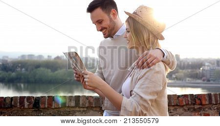 Happy young tourists sightseeing city with map