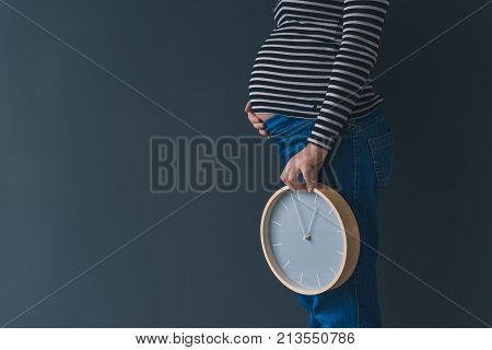 Pregnant female with vintage alarm clock expecting baby in third trimester of pregnancy